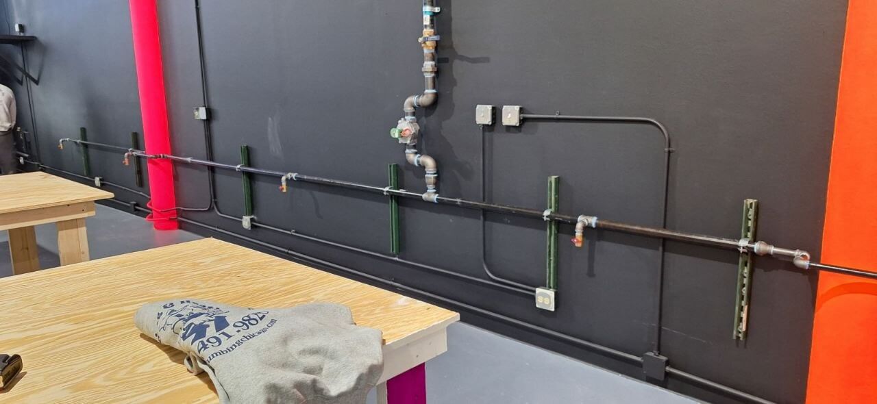 Black iron gas piping installed along a commercial interior wall