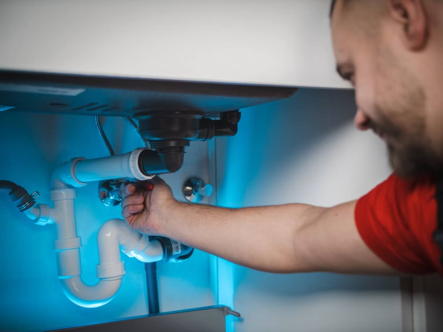 Plumber connecting supply lines under a kitchen sink