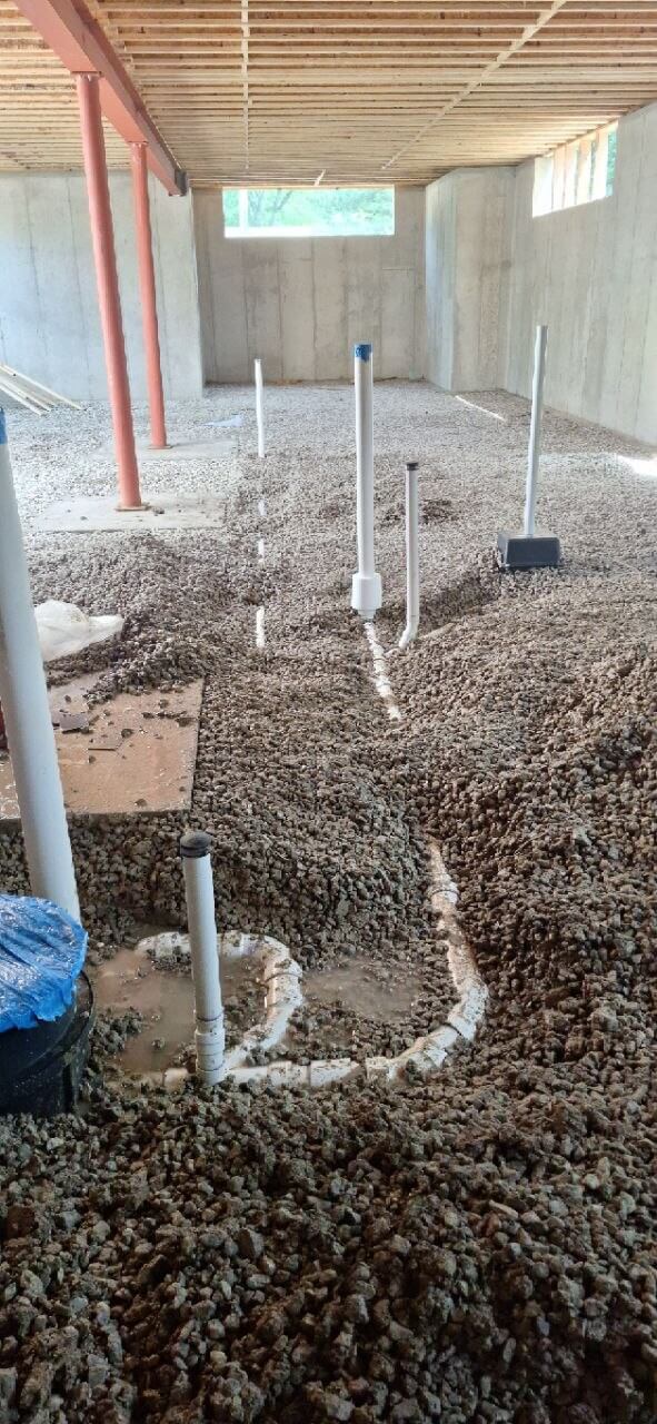 Underground water and sewer line rough-in set in gravel sub-floor during new home construction